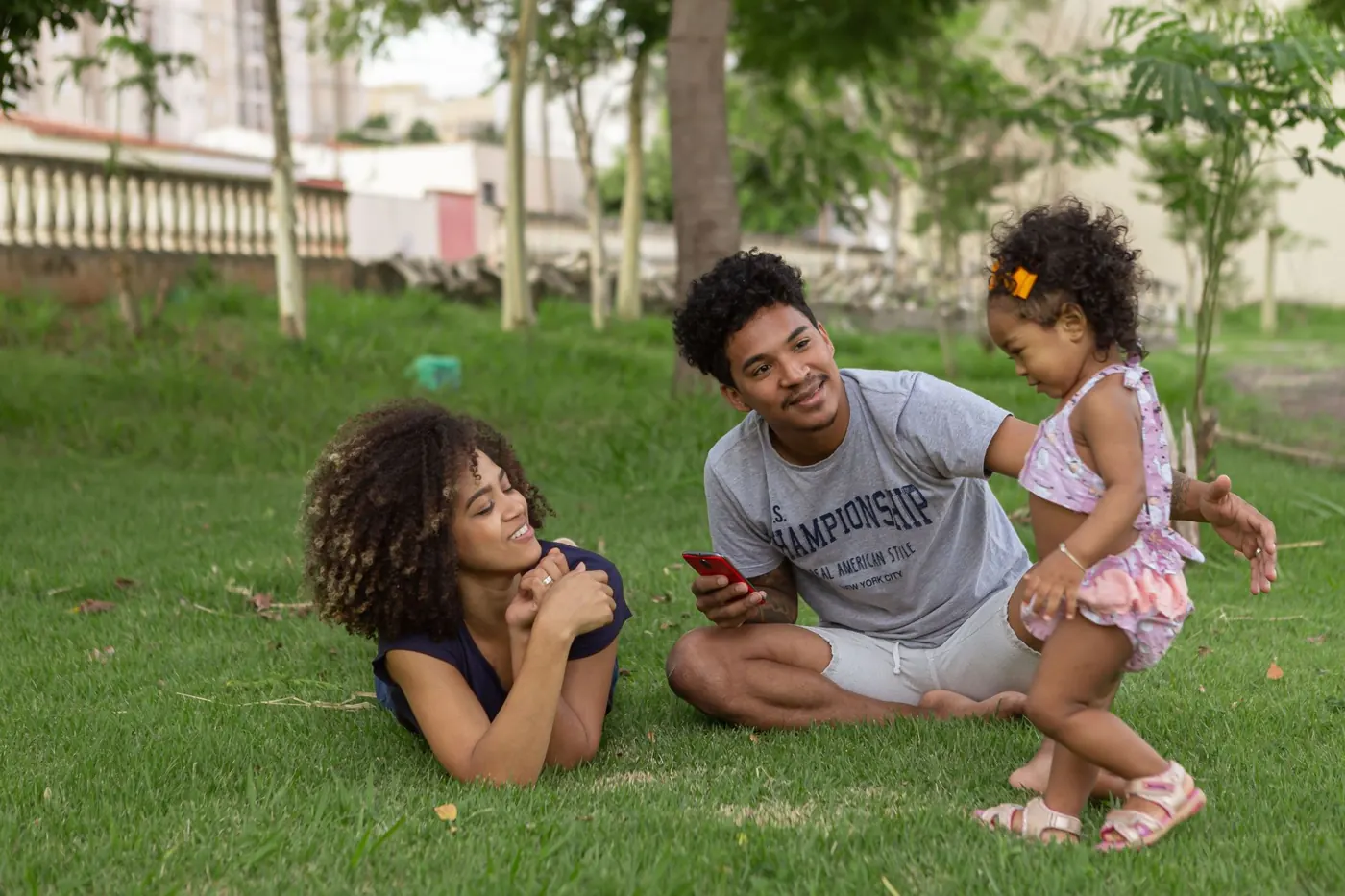 Casal e filha pequena brincando na grama de um parque